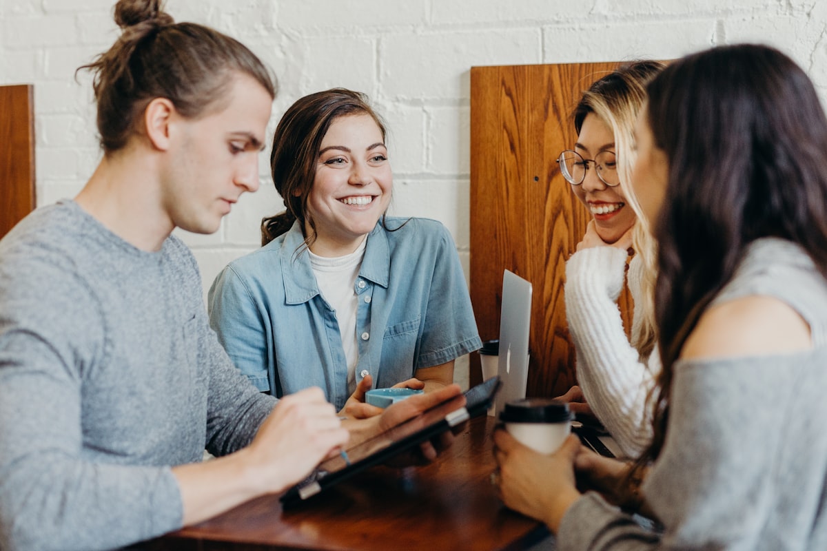 Four colleagues around a table looking at a tablet together